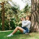 Mom and her Son Have Fun Spending Family Weekends in the Park in Summer, Sitting near a Tree