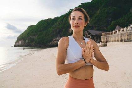 Peaceful woman doing yoga on seacoast in daytime